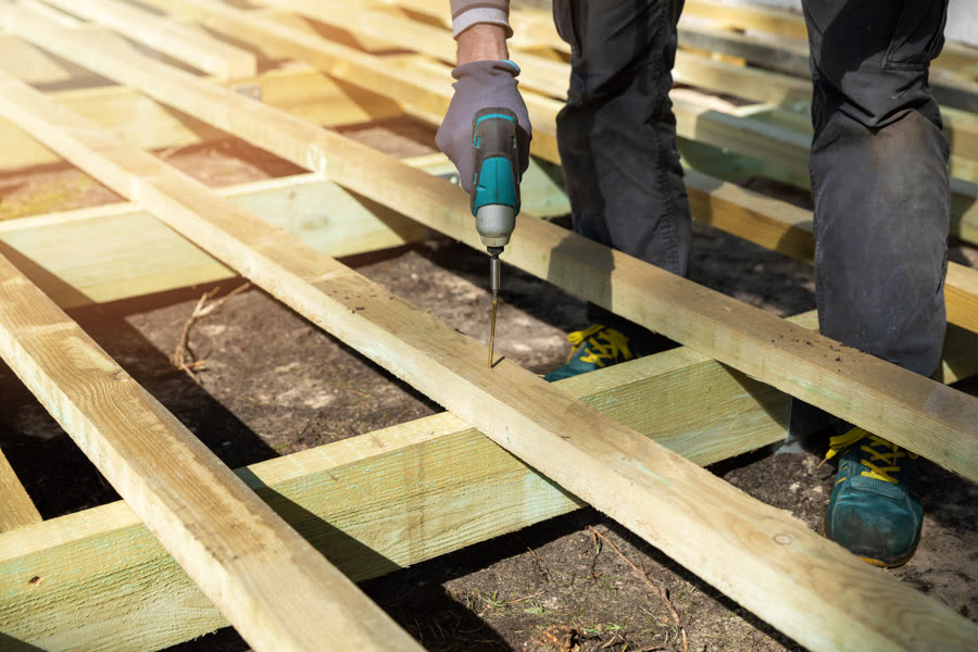 Carpenter fastening deck boards on a new deck frame