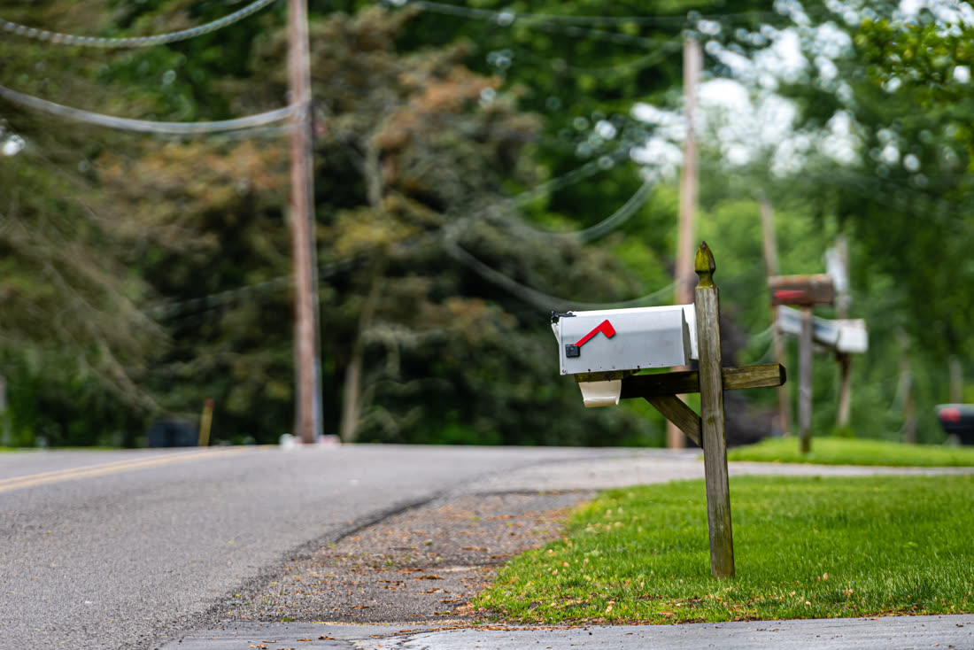 White mailbox on a wooden post at the curb